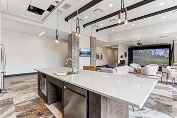 A modern kitchen with a large island and a television in the background.
